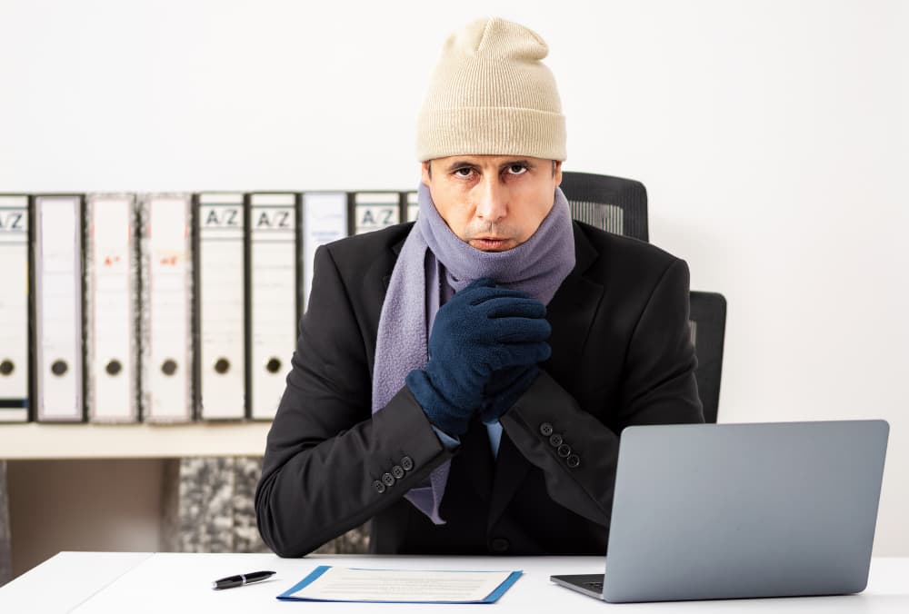 Man in a hat, scarf and gloves, looking cold while he works